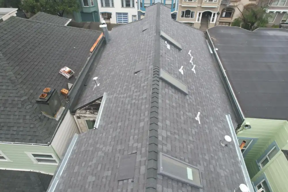 Residential roof with gray shingles and multiple skylights in an urban neighborhood
